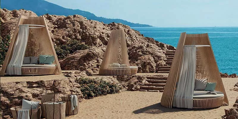 Ethimo Hut Outdoor Loungegruppe in Naturtönen auf sandigem Strand mit Meerblick, ideal für entspannte Momente in luxuriösem Ambiente.