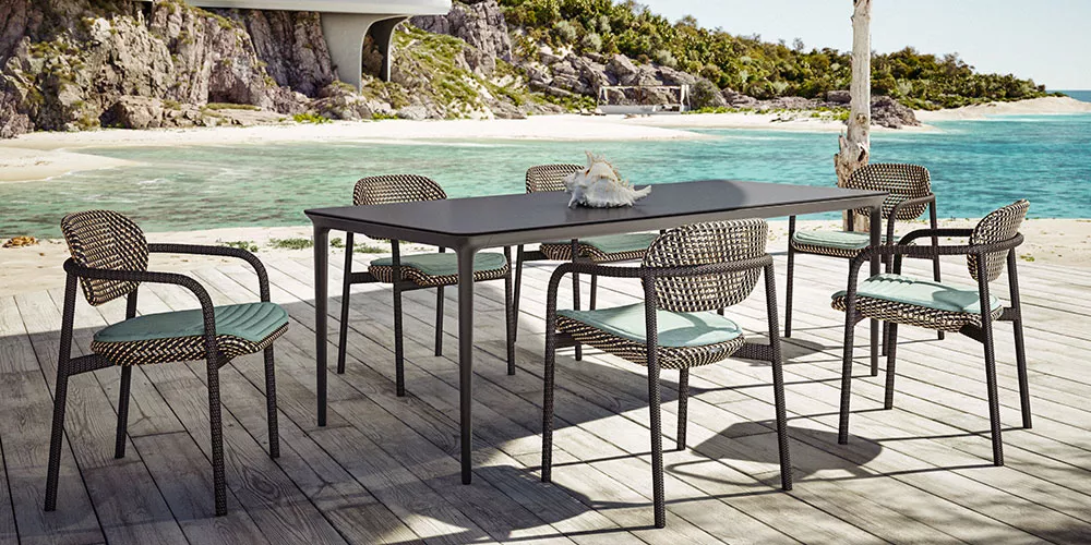 Grau-brauner Outdoor-Tisch mit sechs passenden Stühlen von Villa Schmidt auf einer Terrasse mit Meerblick und tropischem Hintergrund.