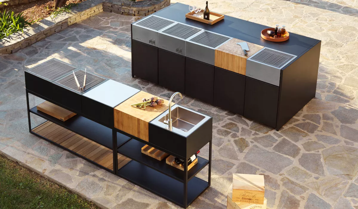 Roshults Outdoor-Küche in Schwarz und Holzoptik, bestehend aus zwei Modulen auf einer Steinplatte im Garten, mit Grill und Spüle.