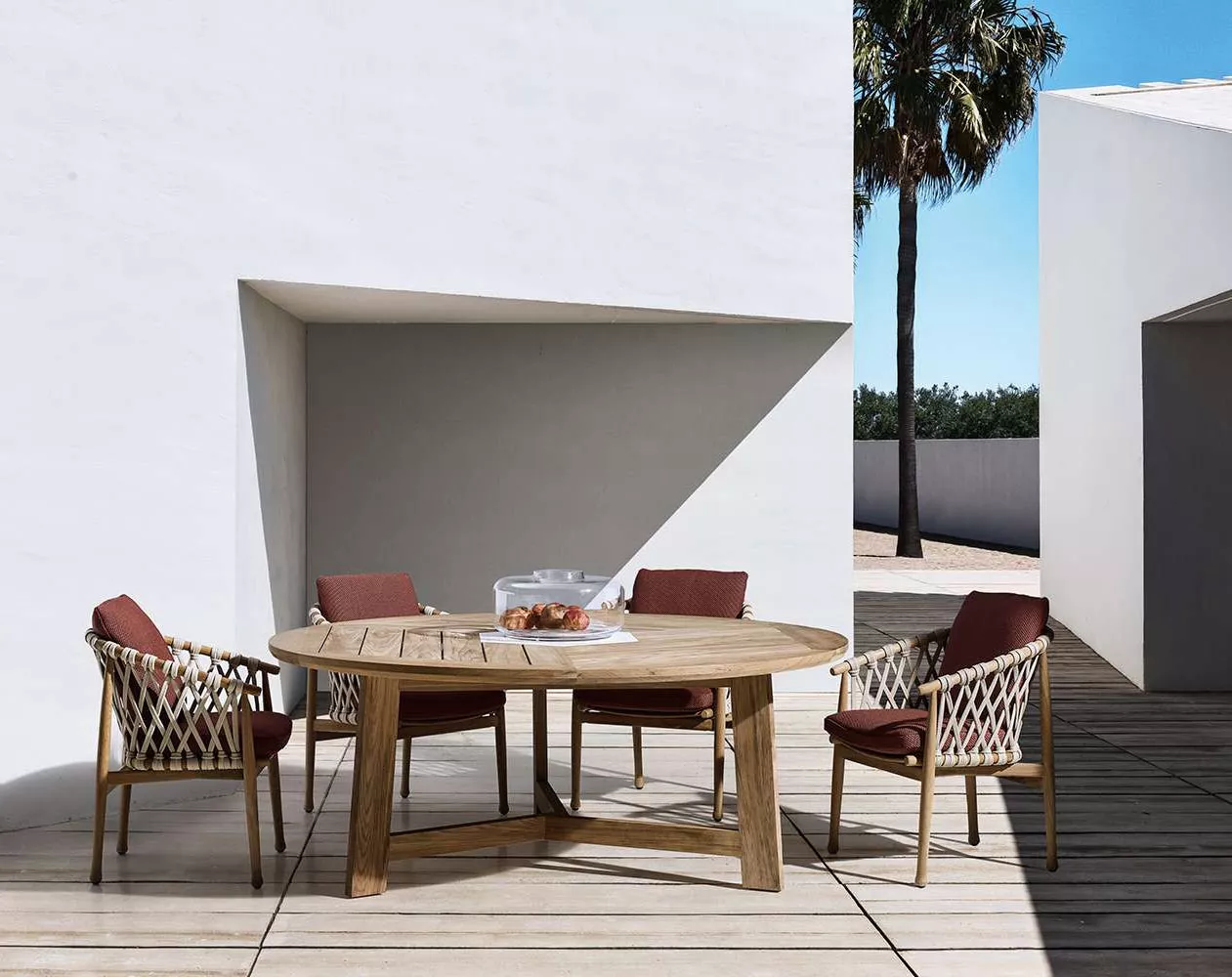 B&B Italia Ginestra Outdoor Essgruppe auf einer Terrasse mit Holzboden und Palmen im Hintergrund