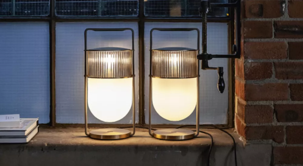 Zwei Poltrona Frau Leuchten in warmem Licht auf einer Fensterbank vor einer Backsteinwand, stimmungsvolle Abendbeleuchtung.