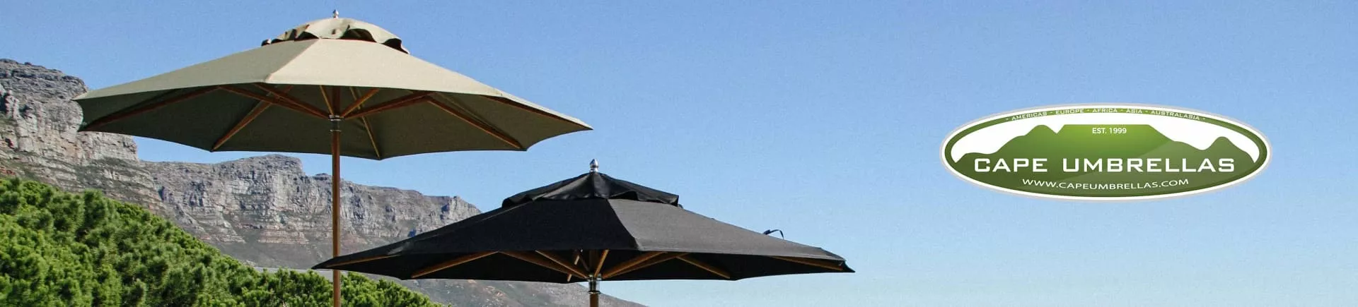 Zwei Cape Umbrellas Sonnenschirme in Beige und Schwarz vor einer Bergkulisse, mit Logo auf der rechten Seite, bei klarem Himmel.