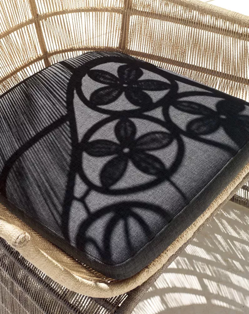 B&B Italia Crinoline Outdoor Sessel mit Abakageflecht zeigt ein Detail des Sitzkissens mit floralem Muster in einer stimmungsvollen Nahaufnahme.