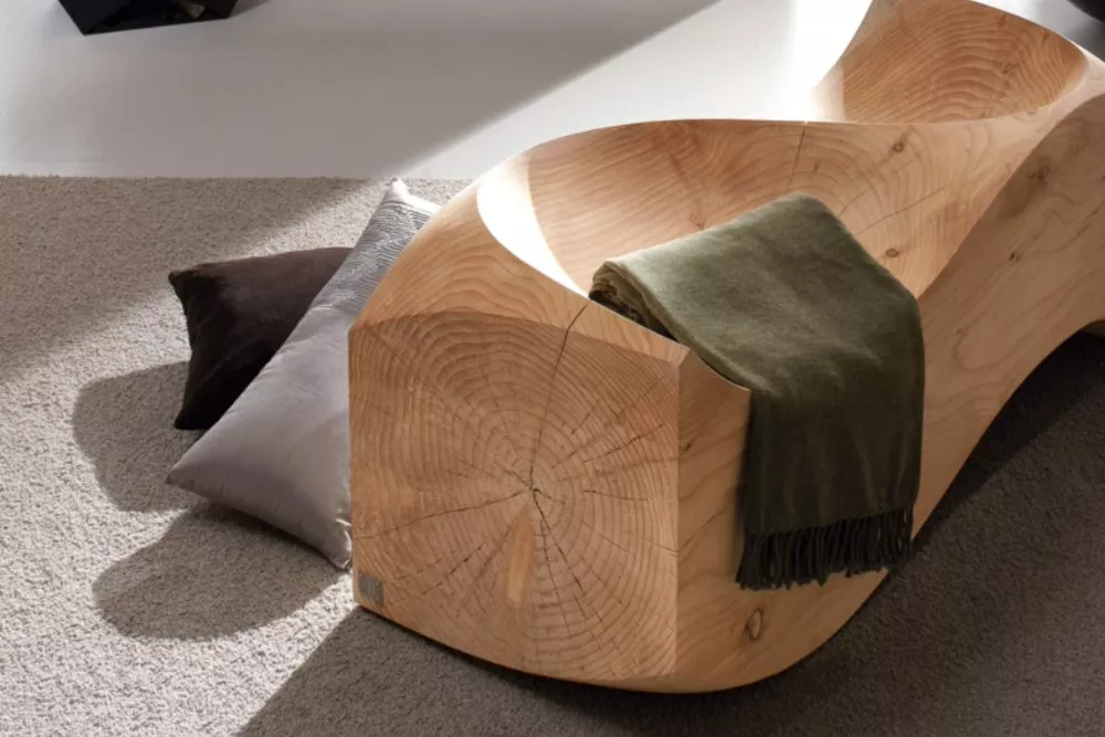 RIVA1920 Bank aus hellem Holz mit grüner Decke, auf grauem Teppich, in einem modernen Raum.