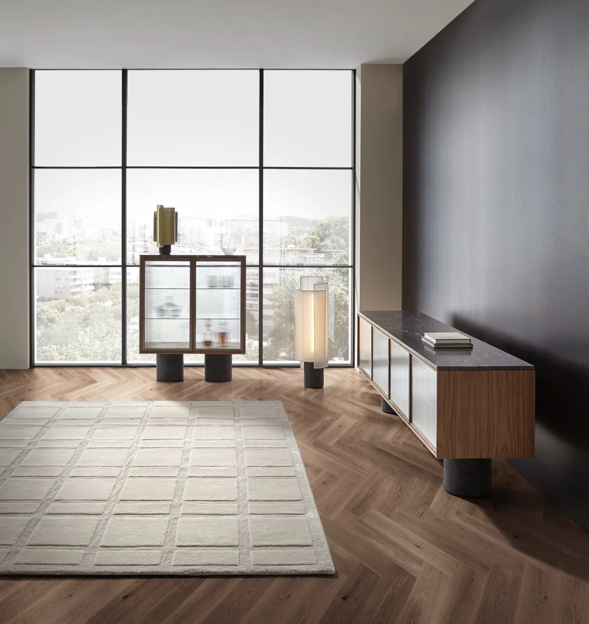 Moderne Wohnzimmeransicht mit Punt Rio Lampe in Beige, neben einem Holzschrank vor einer großen Fensterfront mit Stadtblick.