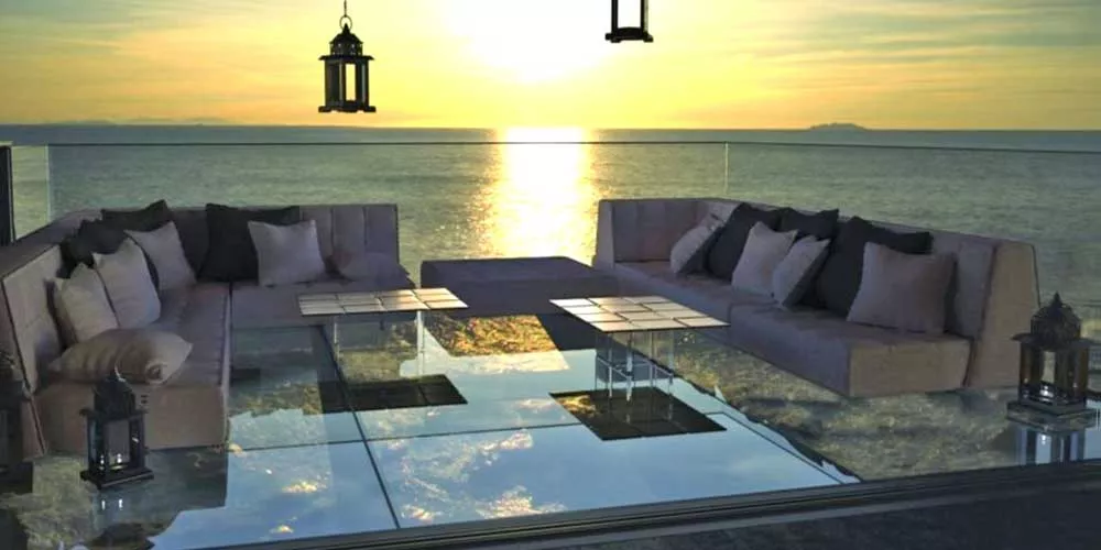 Mayface Mo Loungegruppe Gartenmöbel in Grau auf einer Terrasse mit Meerblick bei Sonnenuntergang, umgeben von Laternen.