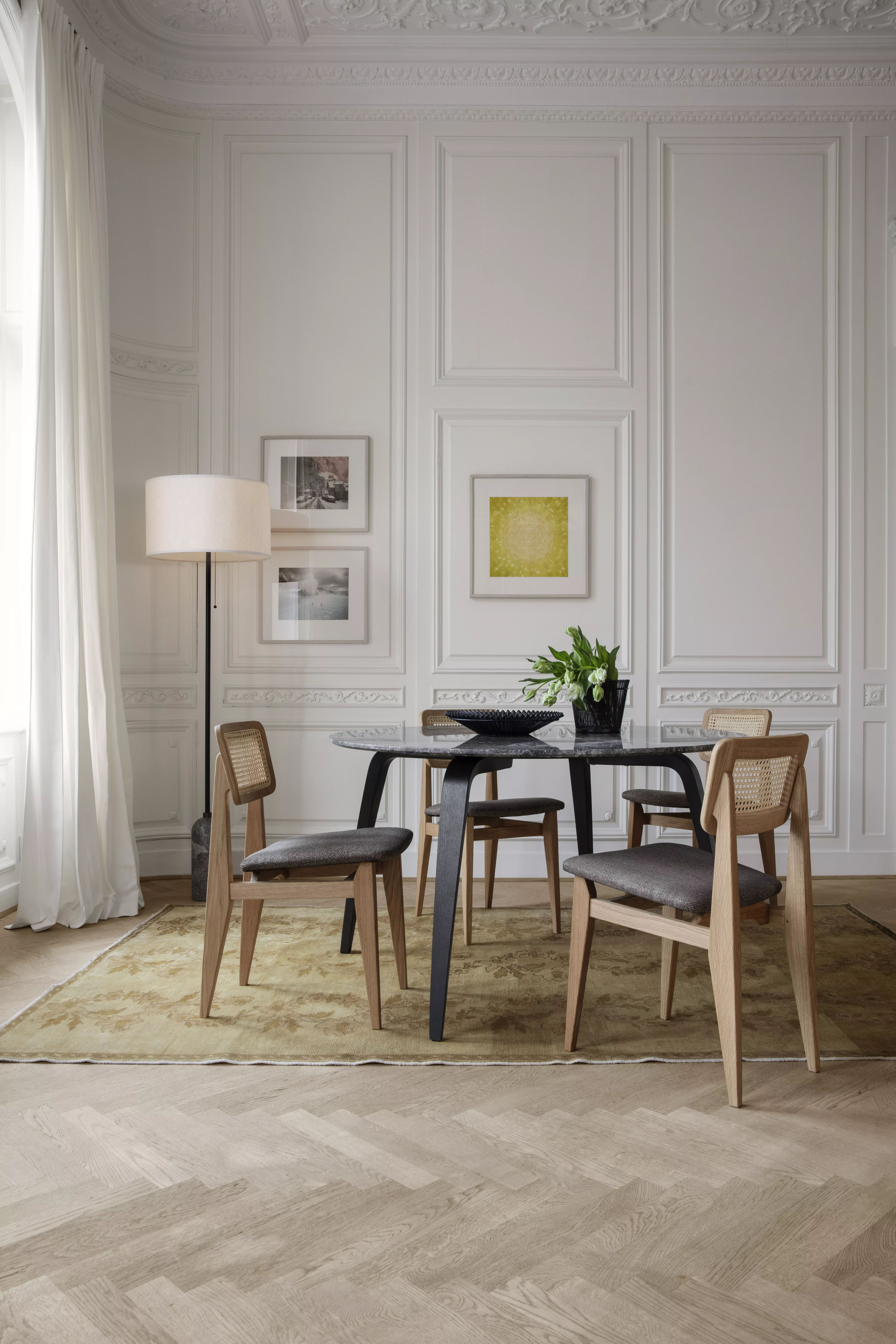 Ein stilvoll eingerichtetes Esszimmer mit GUBI C-Chair Dining Chair Gravity Floor Lamp GUBI Dining Table Mategot Bowl und Mategot Flower Pot.