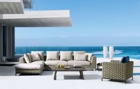 B&B Italia Ray Outdoor Natural Loungeset auf einer Terrasse mit Meerblick und modernem Gebäude im Hintergrund