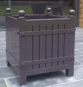 Orangerie Pflanzkübel aus lackiertem Akazienholz steht auf einer Terrasse vor einer Glaswand im Freien