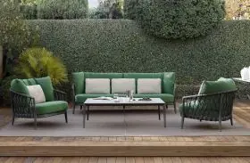 B&B Italia Erica Loungegruppe in grün und beige auf einer Terrasse mit Holzboden und Hecke im Hintergrund mit Tisch und Kissen
