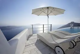 Weißer Glatz Sonnenschirm Fortino auf einer Terrasse mit Meerblick, neben zwei weißen Liegestühlen am Pool.