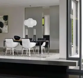 Esszimmer mit B&B Italia Husk Outdoor Armlehnstühlen in Weiß um einen modernen Esstisch mit Kerzenleuchtern und Kunst an der Wand 