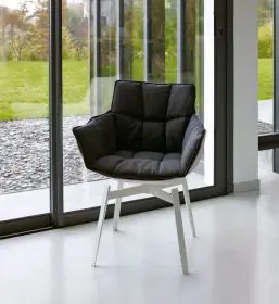 B&B Italia Husk Outdoor Armlehnstuhl in einem modernen Raum mit großen Fenstern und Blick auf einen grünen Garten 