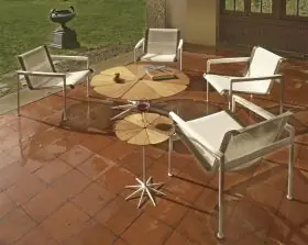 Knoll Studio 1966 Collection Lounge Sessel auf einer Terrasse mit runden Holztischen und einem Buch auf einem der Tische