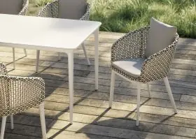 DEDON BELLMONDE Gartenmöbel auf einer Holzterrasse mit grünem Rasen im Hintergrund vier Stühle und ein Tisch in einer entspannten Atmosphäre