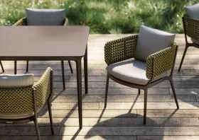 DEDON BELLMONDE Stühle und Tisch auf einer Holzterrasse im Freien umgeben von grüner Natur und Sonnenlicht