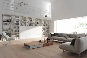 Helles Wohnzimmer mit Interlübke Studimo Regal in Weiß, gefüllt mit Büchern und Dekorationen, neben grauem Sofa und modernem Sessel.