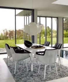 B&B Italia Husk Outdoor Armlehnstuhl in Weiß und Schwarz an einem Esstisch in einem modernen Esszimmer mit großen Fenstern und Blick auf den Garten
