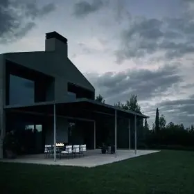B&B Italia Borea Loungesofa steht auf einer Terrasse vor einem modernen Haus bei Dämmerung mit einem gedeckten Tisch und Stühlen im Freien