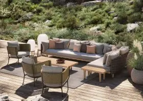 DEDON BELLMONDE Lounge Set auf einer Terrasse inmitten einer grünen Landschaft mit mehreren Sesseln einem Sofa und einem Tisch in einer entspannten Atmosphäre