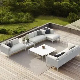Dedon Izon Kollektion weiße Outdoor-Sofas und Tisch auf einer Holzterrasse mit grüner Landschaft im Hintergrund 