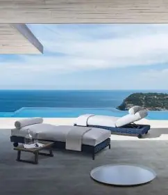 B&B Italia Ray Outdoor Fabric Sonnenliege 203 cm mit Rollen verstellbar am Pool mit Blick auf das Meer und eine Insel im Hintergrund