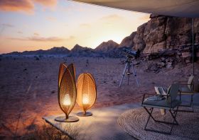 Dedon Mysterious Desert Seax Scoora Lampen leuchten in der Dämmerung in einer Wüstenlandschaft neben einem Teleskop und einer Sitzgruppe