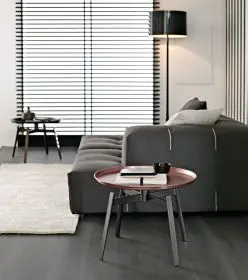 B&B Italia Husk Outdoor Beistelltisch 62,5 cm in einem modernen Wohnzimmer mit grauem Sofa und Lampe im Hintergrund 
