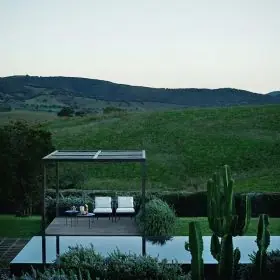 B&B Italia Borea Loungesofa steht auf einer Terrasse mit Blick auf eine grüne Landschaft und einen Pool im Hintergrund