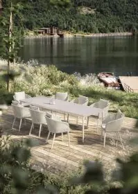 DEDON BELLMONDE Esstisch und Stühle auf einer Terrasse mit Blick auf einen See und ein Boot im Hintergrund in einer idyllischen Landschaft