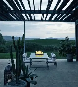 B&B Italia Borea Essgruppe auf einer Terrasse mit Blick auf eine grüne Landschaft bei Dämmerung mit Kerzen auf dem Tisch und Pflanzen im Vordergrund